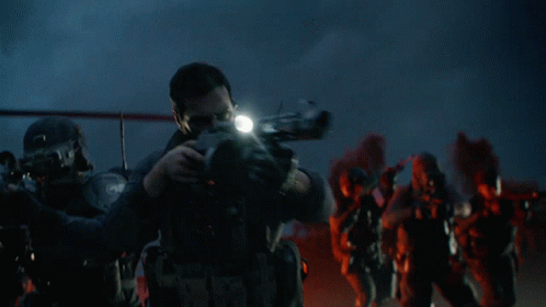 A Man With A Beard Is Holding A Gun With A Light On It GIF
