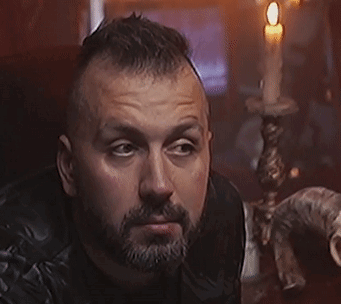 A Man With A Beard Is Holding A Knife In His Hand GIF