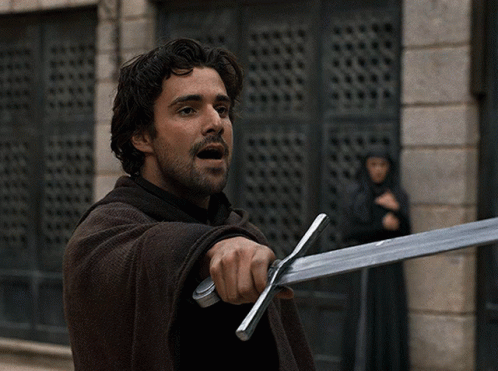 A Man With A Beard Is Holding A Large Sword GIF