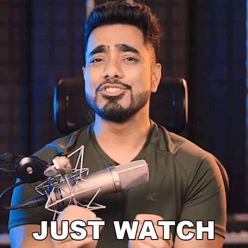 A Man With A Beard Is Holding A Microphone And Says " Just Watch " GIF