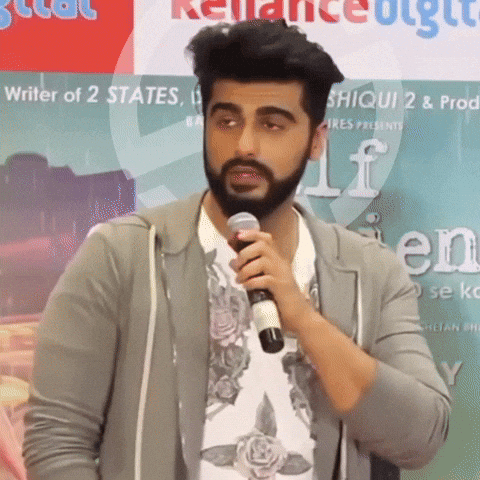 A Man With A Beard Is Holding A Microphone In Front Of A Sign That Says ' Writer Of 2 States ' GIF