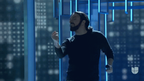 Man With Beard Holding Microphone In Front Of Window GIF