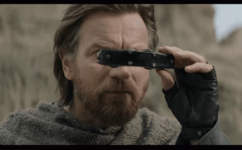 A Man With A Beard Is Holding A Pair Of Binoculars GIF
