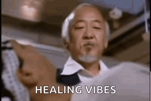 a man with a beard is holding a piece of paper in his hand and says `` healing vibes '' .
