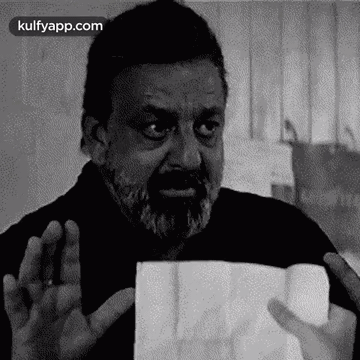 A Man With A Beard Is Holding A Piece Of Paper . GIF