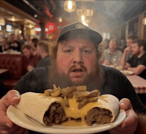 A Man With A Beard Is Holding A Plate Of Food With A Gk Hat On GIF