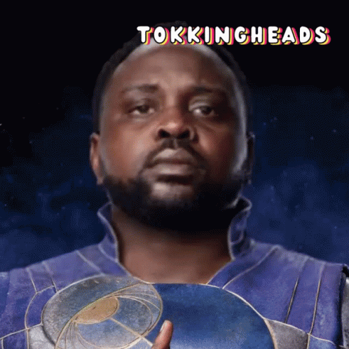 A Man With A Beard Is Holding A Shield With The Words Tokingheads Below Him GIF