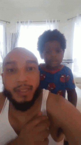 A Man With A Beard Is Holding A Small Child On His Shoulders GIF