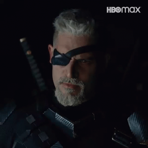 A Man With A Beard Is Holding A Sword And Wearing A Black Eye Patch With The Word Deathstroke On It GIF