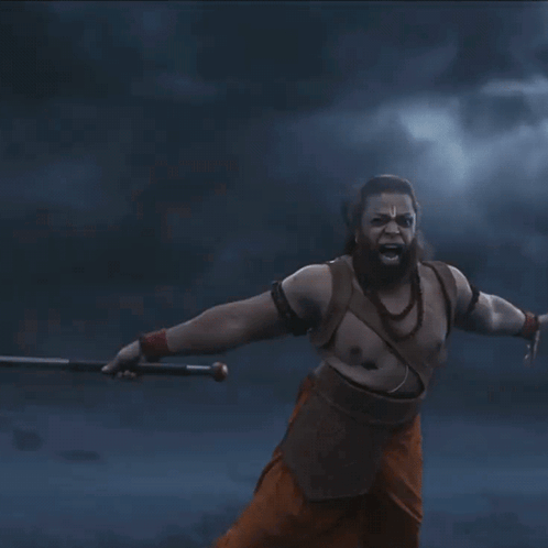 A Man With A Beard Is Holding A Sword In His Hands GIF