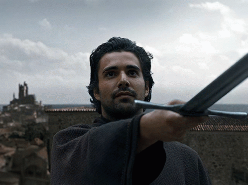 A Man With A Beard Is Holding A Sword In His Right Hand GIF