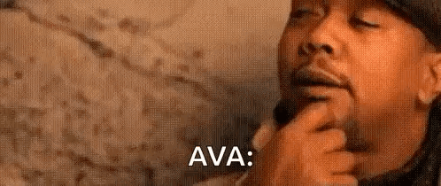 A Man With A Beard Is Holding His Hand To His Chin And Thinking . GIF
