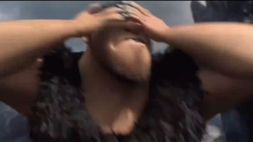 A Man With A Beard Is Holding His Head In Pain . GIF