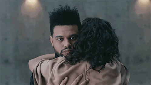 A Man With A Beard Is Hugging A Woman With Curly Hair .. GIF