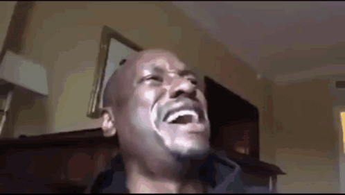 A Man With A Beard Is Laughing In A Room . GIF