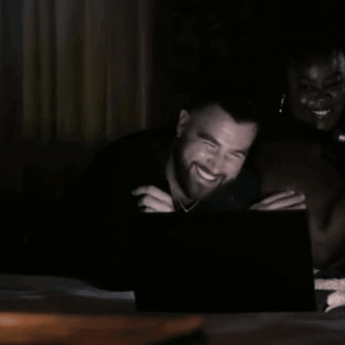 A Man With A Beard Is Laughing While Looking At A Laptop Screen . GIF