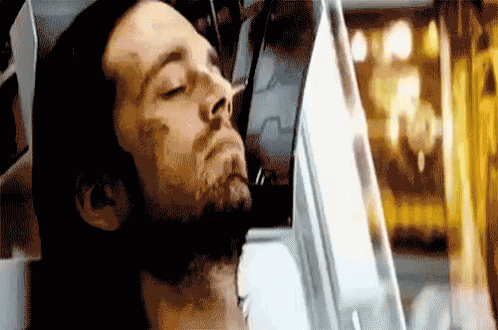 A Man With A Beard Is Laying Down In A Chair With His Eyes Closed . GIF
