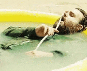 A Man With A Beard Is Laying In A Pool Drinking Water Through A Straw GIF