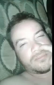 A Man With A Beard Is Laying In Bed With His Eyes Closed . GIF