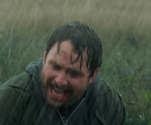 A Man With A Beard Is Laying In The Rain With His Eyes Closed GIF