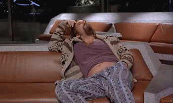 A Man With A Beard Is Laying On A Couch . GIF