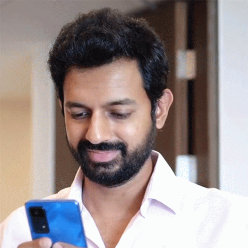 A Man With A Beard Is Looking At A Blue Cell Phone GIF