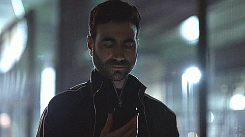 A Man With A Beard Is Looking At A Cell Phone GIF