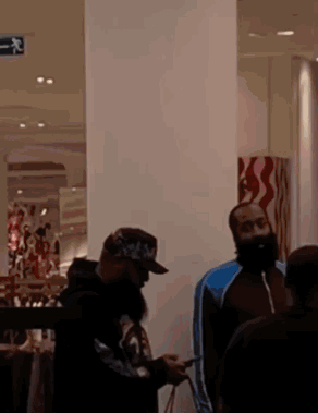 A Man With A Beard Is Looking At His Phone While Standing In A Store GIF