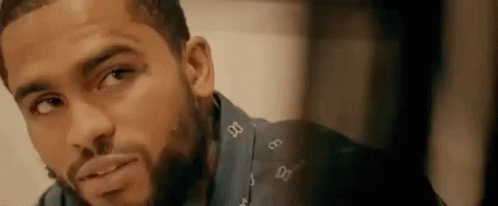 A Man With A Beard Is Looking At The Camera And Smiling . GIF