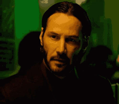 a man with a beard is looking at the camera in a dark room