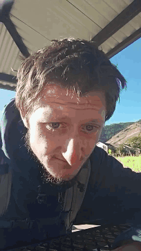 A Man With A Beard Is Looking At The Camera With His Eyes Closed GIF