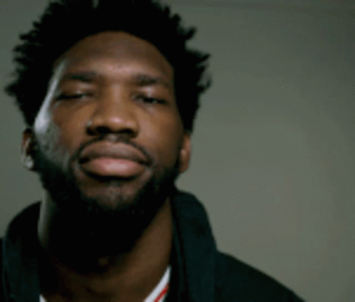 A Man With A Beard Is Looking At The Camera With His Eyes Closed GIF