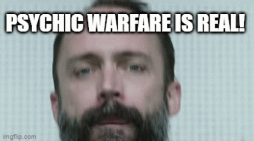 A Man With A Beard Is Looking At The Camera With The Words `` Psychic Warfare Is Real '' Written Below Him . GIF