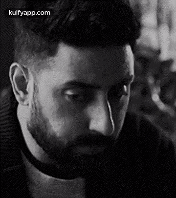 A Man With A Beard Is Looking Down In A Black And White Photo . GIF