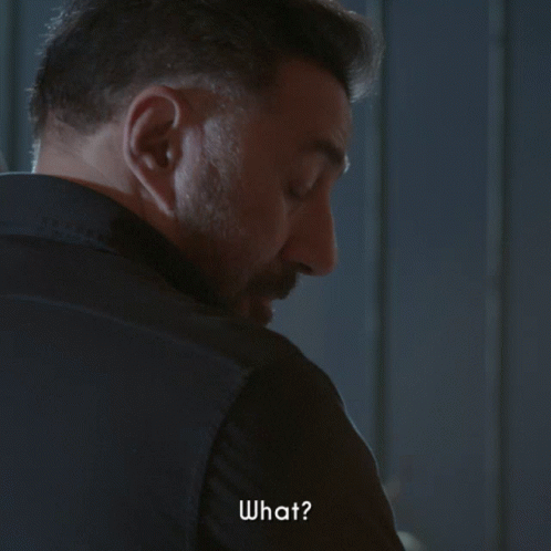 A Man With A Beard Is Looking Over His Shoulder And Says " What " GIF