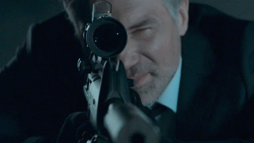 A Man With A Beard Is Looking Through A Scope GIF