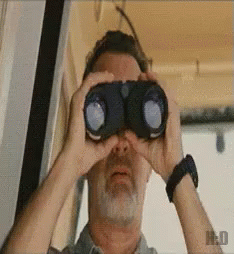 A Man With A Beard Is Looking Through Binoculars With The Letter H On The Bottom Left GIF