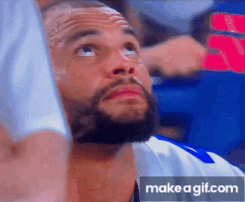 A Man With A Beard Is Looking Up At The Sky While Sitting In A Stadium . GIF
