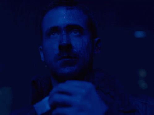 a man with a beard is looking up in a dark blue room