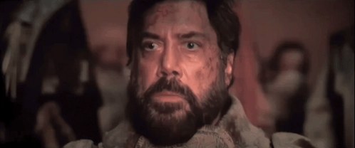 A Man With A Beard Is Looking Up In A Dark Room GIF