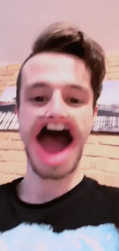A Man With A Beard Is Making A Face With His Mouth Open . GIF