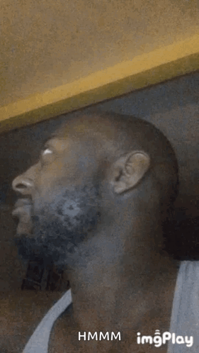 A Man With A Beard Is Making A Funny Face In A White Tank Top . GIF