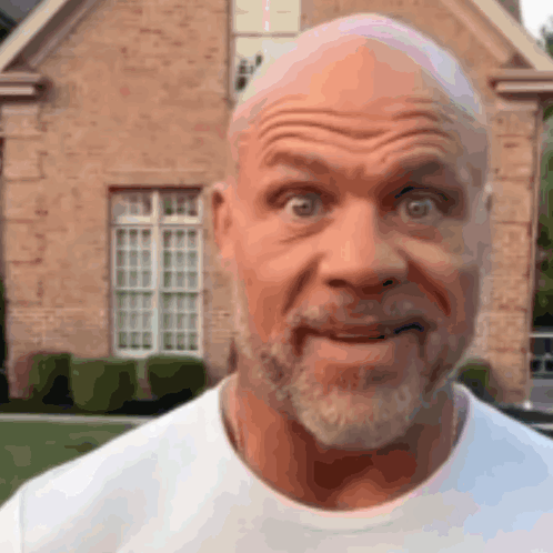 A Man With A Beard Is Making A Funny Face In Front Of A Brick House GIF