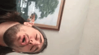 a man with a beard is making a funny face in front of a painting .