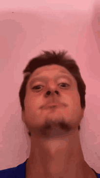 A Man With A Beard Is Making A Funny Face In Front Of A Pink Background . GIF