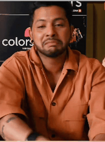 A Man With A Beard Is Making A Funny Face In Front Of A Poster That Says Colors GIF