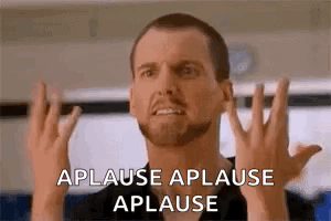 A Man With A Beard Is Making A Funny Face While Applauding . GIF