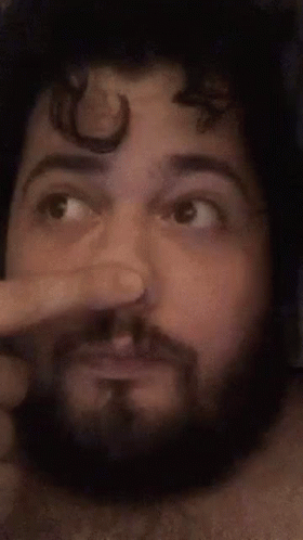 A Man With A Beard Is Making A Funny Face While Holding His Nose . GIF
