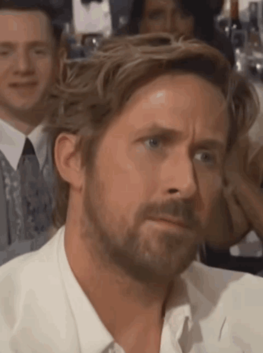 A Man With A Beard Is Making A Funny Face While Sitting In A Crowd . GIF