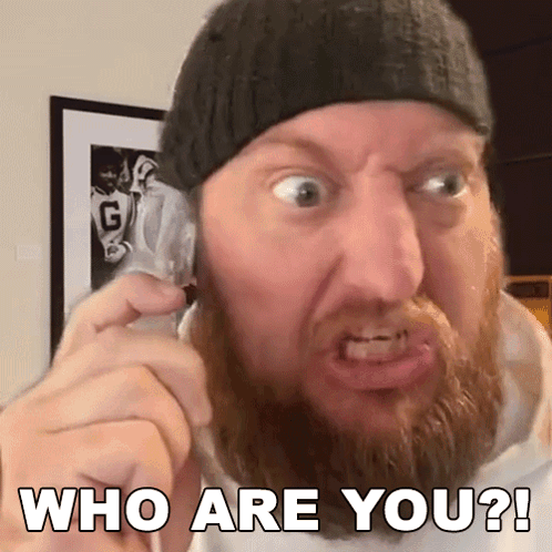 A Man With A Beard Is Making A Funny Face While Talking On A Cell Phone And Says Who Are You ? GIF